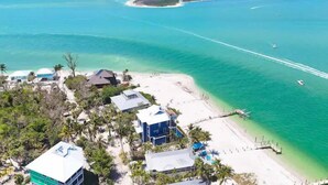 An aerial view of a coastal area with a beach, clear turquoise waters, and a small island in the distance. - Gran Palacio-Beachfroont,Pool, Fishing & 360 Views, North Captiva Luxury Escape (Lee County)