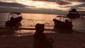 A beach scene with boats and a pier during sunset. - Sharilaa Coral Perhentian Resort (Pulau Perhentian Kecil)
