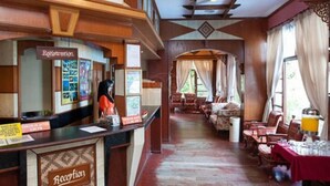 A reception area with a wooden reception desk, a registration sign, and a seating area with tables and chairs. - Sharilaa Coral Perhentian Resort (Pulau Perhentian Kecil)