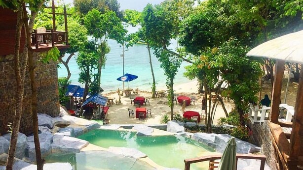 A pool area with rock formations, outdoor seating, and a view of the beach. - Sharilaa Coral Perhentian Resort (Pulau Perhentian Kecil)