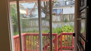 Una habitación con puerta corrediza de vidrio que da a una terraza exterior con barandal rojo.