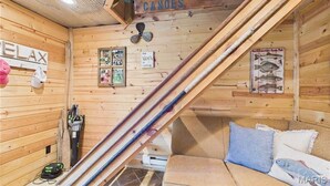 Mökki, jonka sisätilat ovat puuta, ja jossa on sohva, kyltti, jossa lukee ”Täällä myydään vanhan kaupungin kanoja”, sekä kalastukseen liittyviä koriste-esineitä.