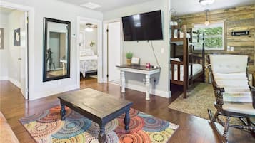 A living room with a wooden coffee table, a colorful rug, a television, and a rocking chair.
