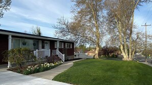 Une maison de banlieue avec un jardin devant, une allée et une vue sur la rue.