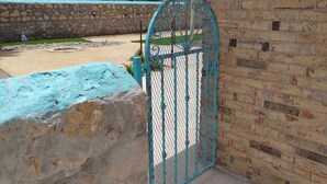 A turquoise metal gate with a decorative design, a stone wall, and a brick wall. - 3-bdm home, sunny El Paso near shops, medical, schools, restaurants, & more (El Paso)