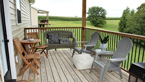 Una terraza de madera con mobiliario exterior, incluyendo una mesa, sillas y un sofá.