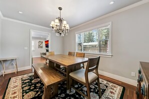 A dining room with a wooden table, benches, and a chandelier.