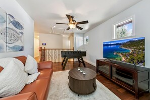 A living room with a sofa, a coffee table, a television, and a ceiling fan. - Tahoe Keys Cozy Mountain Retreat 3BR, 3BA (South Lake Tahoe)