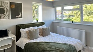 Une chambre à coucher avec un lit, un bureau et une fenêtre donnant sur un paysage verdoyant.