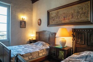 A bedroom with two beds, a large painting, and a window.