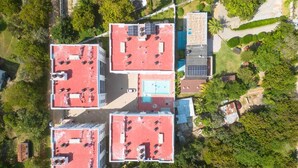An aerial view of a residential complex with four buildings, each featuring a red roof and solar panels.