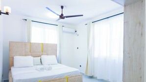 A modern bedroom with a large bed, a ceiling fan, and a built-in air conditioning unit.