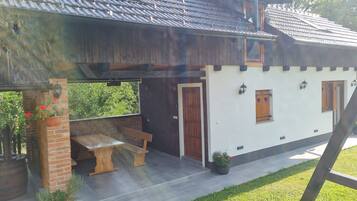 Une maison à deux étages avec un patio, un banc en bois et des plantes en pot.