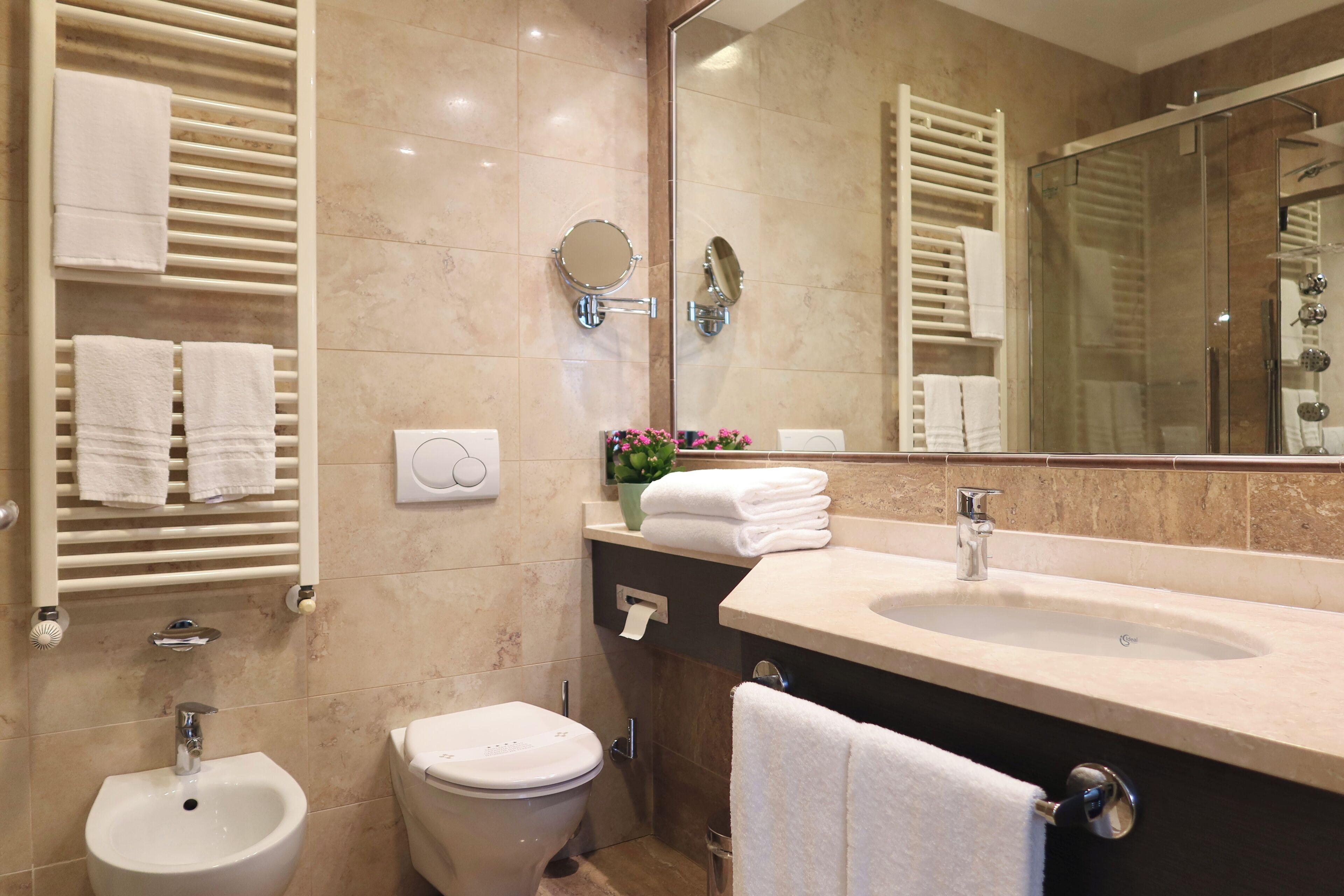 Ein modernes Badezimmer mit Bidet, Toilette, Waschbecken und einem großen Spiegel.