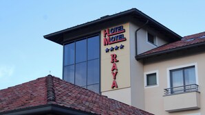 A hotel sign with the name "Hotel Motel Raya" and a modern building with a red-tiled roof. - Raya Hotel (Mediglia)
