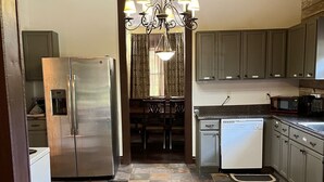 A kitchen with a stainless steel refrigerator, a dishwasher, and a microwave. There is a chandelier hanging from the ceiling.