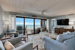 A spacious living room with a view of the ocean, a ceiling fan, and a flat-screen TV. - Amelia by the Sea (Fernandina Beach)
