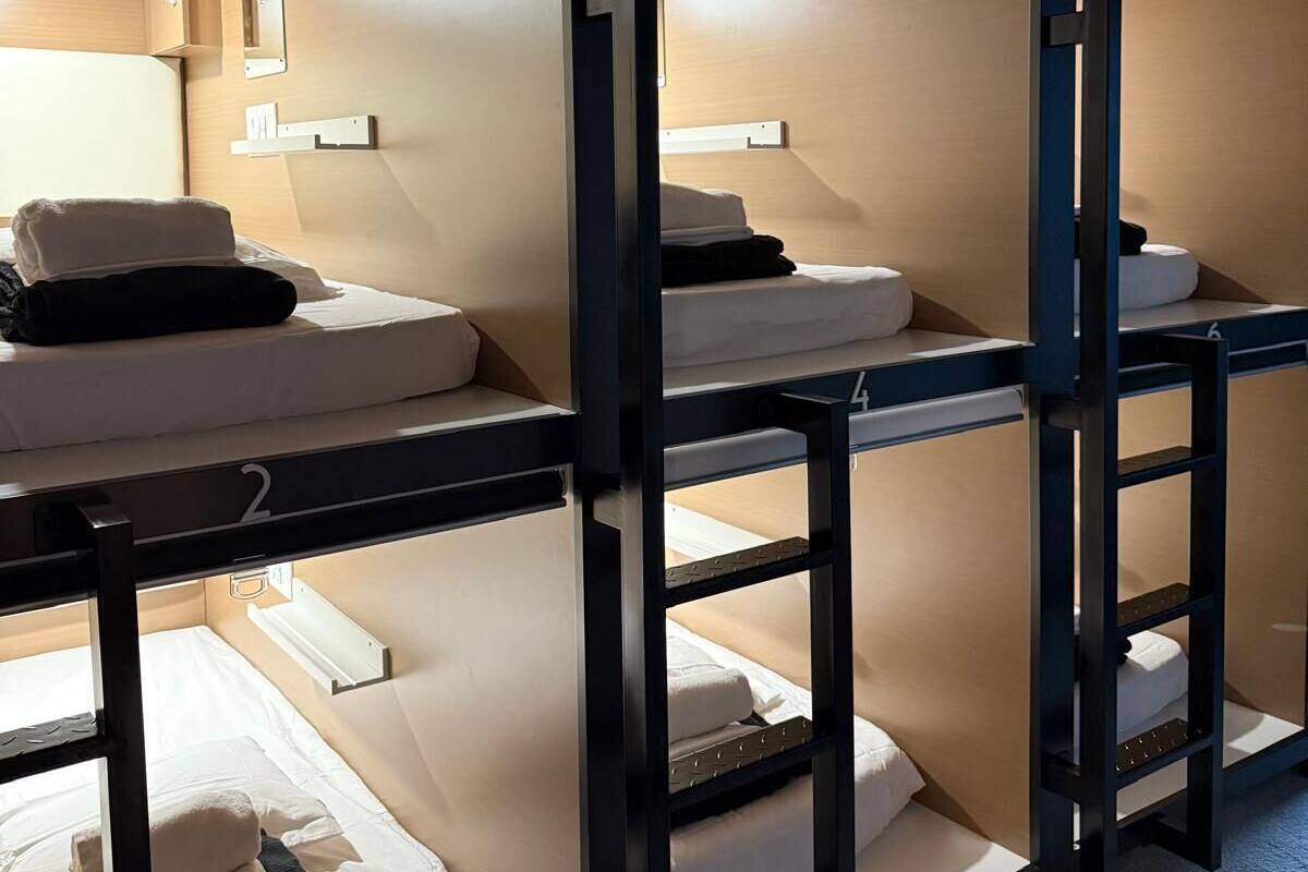 A series of bunk beds with individual compartments, each with a mattress, pillows, and a small shelf.