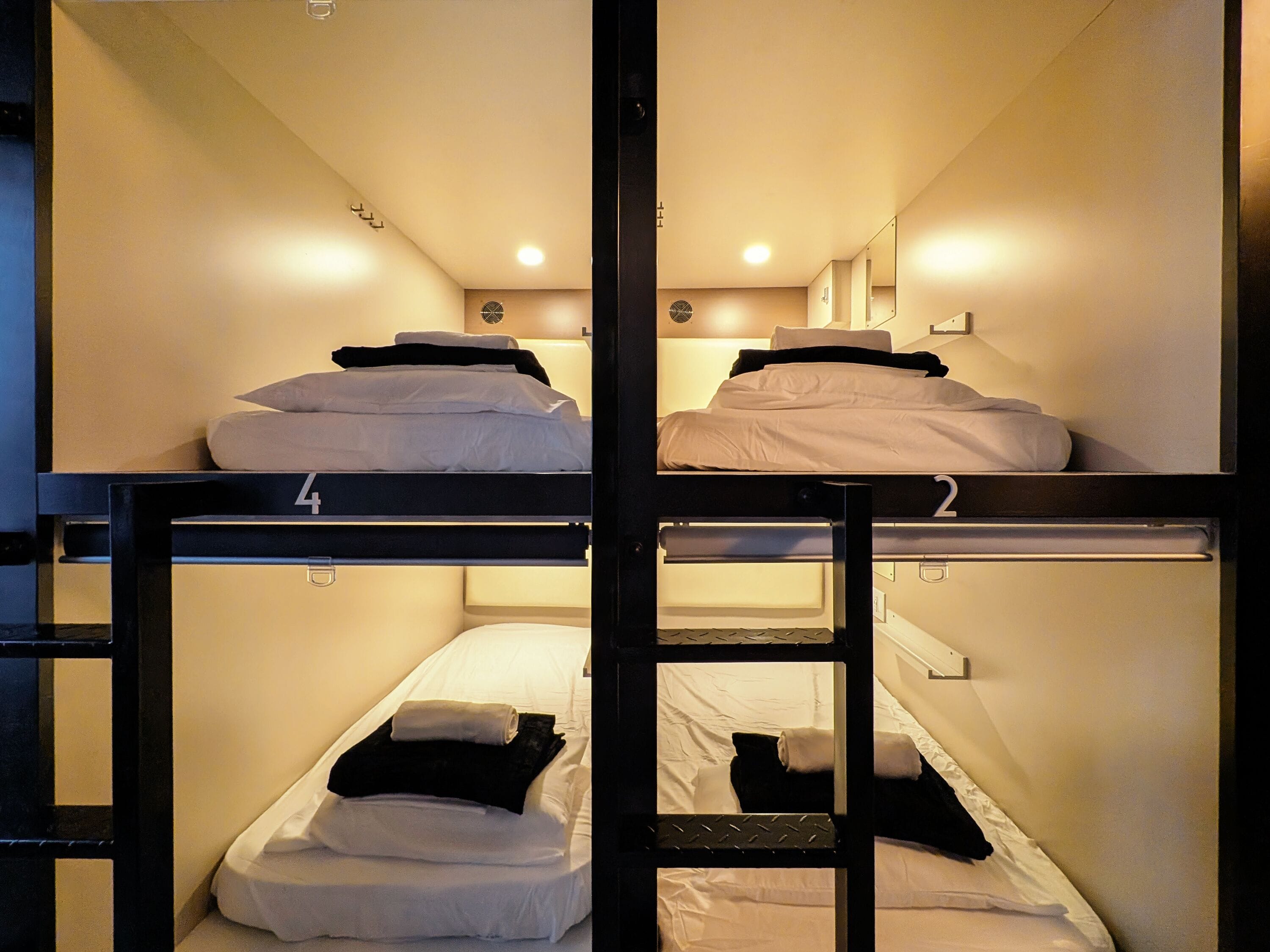Un dormitorio con literas, camas numeradas y un ventanal pequeño.