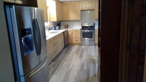 A kitchen with wooden cabinets, a stainless steel refrigerator, an oven, and a dishwasher.