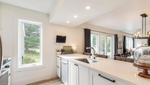 Una cucina moderna con una grande isola, elettrodomestici integrati e vista sull'esterno.