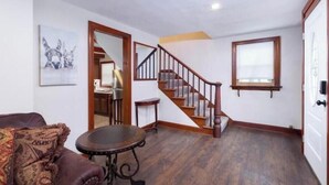 Ein Wohnzimmer mit einer Holztreppe, einem Esstisch und einem Sofa.