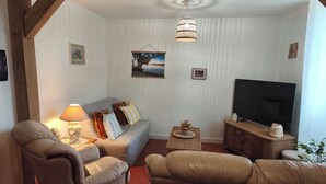 A living room with a sofa, two armchairs, a TV, and a lamp. - Gîte chez Renée (Azay-le-Ferron)