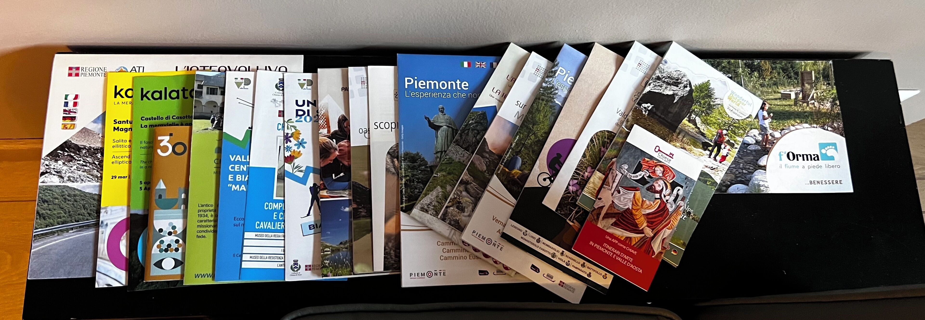 Une collection de brochures et de cartes touristiques, rangées sur une étagère.
