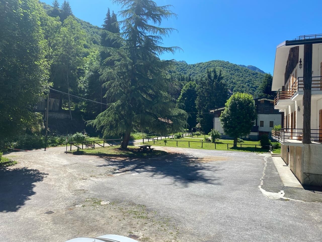 Un estacionamiento con una mesa de picnic y un sendero cercado que conduce a un edificio.