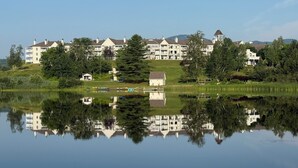Vue sur un quartier résidentiel au bord d’un lac, avec de nombreuses maisons à deux étages, un petit quai et un reflet net dans l’eau.