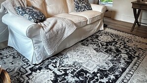 Un salon chaleureux avec un canapé blanc, un tapis à motifs et un lustre.
