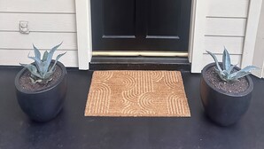A black front door with a mailbox and a security camera above it.