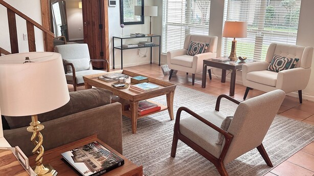 A spacious living room with a large window, a wooden coffee table, and a comfortable seating area.