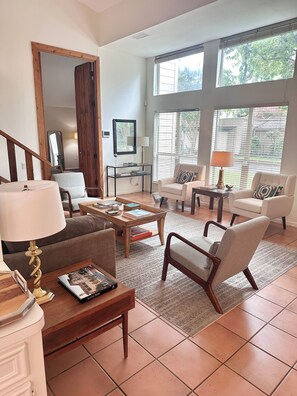 Un amplio salón con un gran ventanal, una mesa de centro de madera y una zona de estar confortable.