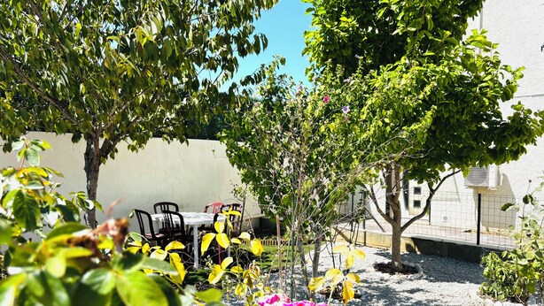 A garden area with a table and chairs, surrounded by trees and plants. - 6-person house with garden in quiet neighborhood (Cournonterral)