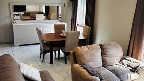 A modern living room with a sofa, a coffee table, and a dining area with chairs and a table. - 6-person house with garden in quiet neighborhood (Cournonterral)