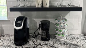 A kitchen with white tiled walls, black shelves, and a coffee maker on the counter. - Green Cottage / Explore Trails, Ride Bikes & Golf! (Bella Vista)