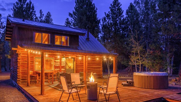 Une cabane en rondins dotée d’une terrasse, d’un espace salon extérieur et d’un jacuzzi.