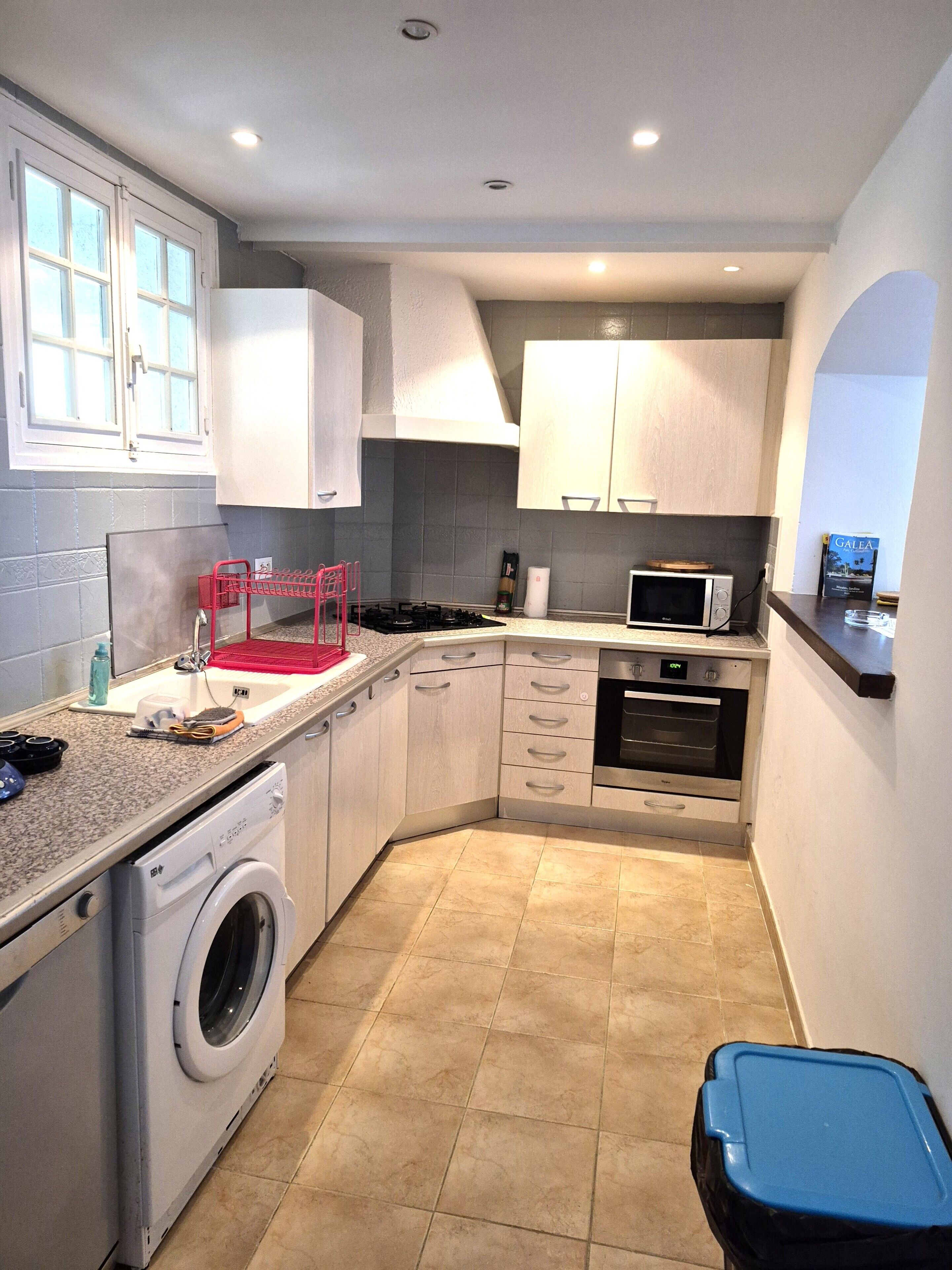 Een kleine keuken met een wasmachine, magnetron en een klein oven.