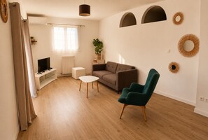 A modern living room with a sofa, a green armchair, a small table, and a television.
