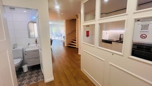 Une cuisine moderne avec des meubles blancs, un four encastré et une fenêtre donnant sur le salon.