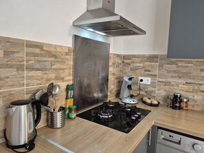 A modern kitchen with a gas stove, a coffee maker, and a kettle.