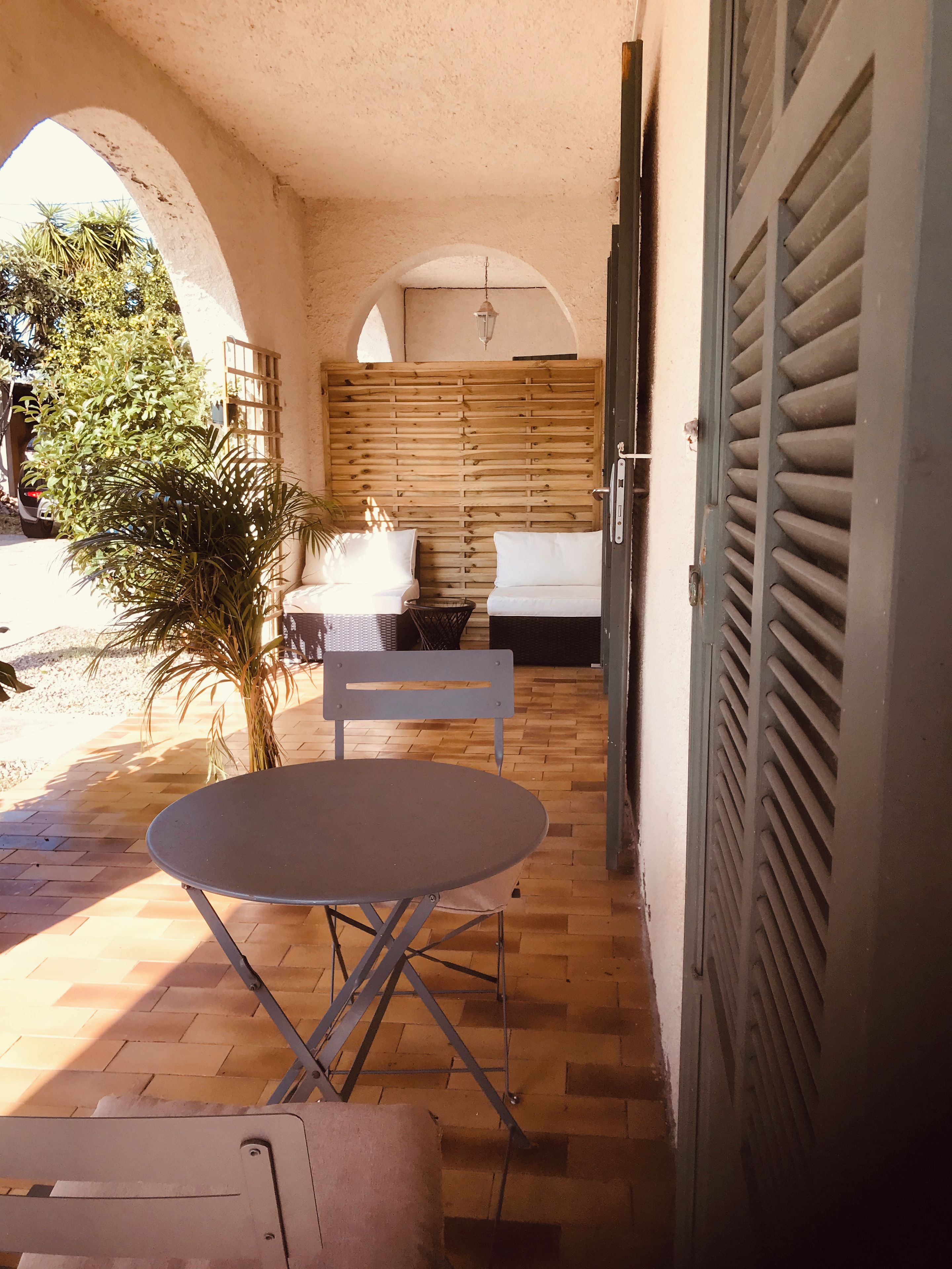 A patio area with a table and chairs, a sofa, and a wooden wall.