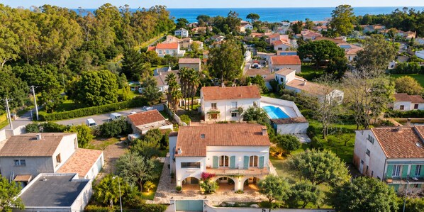 A residential area with houses, a swimming pool, and a view of the sea.