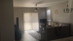 A living room with a sofa, a coffee table, a TV, and a ceiling fan. - Stunning Avondale Home! (Avondale)
