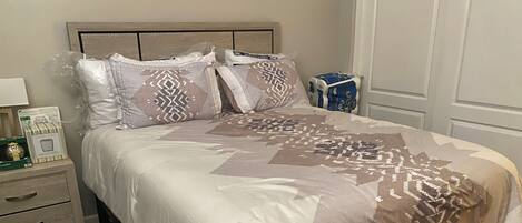 A neatly made bed with patterned bedding, a bedside table with a lamp, and a box of tissues.