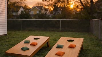 Two wooden bean bags with cushions on a grassy lawn.