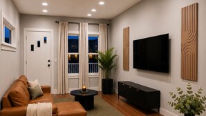Una sala de estar moderna con sofá, mesa de centro, televisión y un comedor con sillas y mesa.