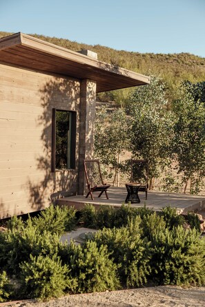 A wooden building with a covered patio area, two chairs, and a table.