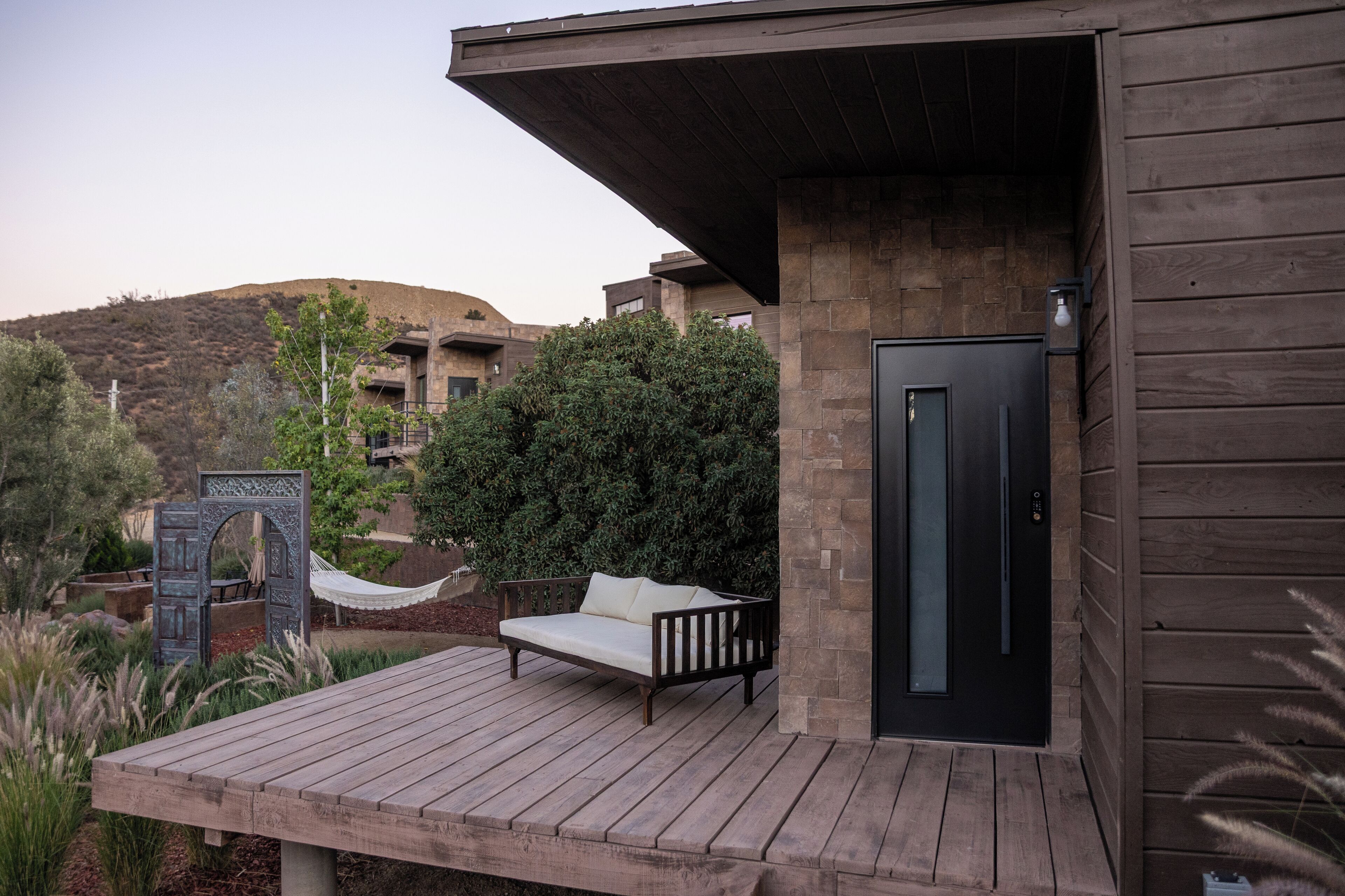 A wooden deck with a sofa and a door to a building.